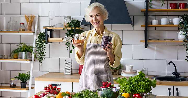 donna anziana in cucina con vegetali